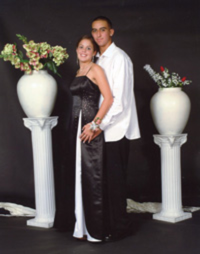 Young couple posing elegantly between two white floral vases.