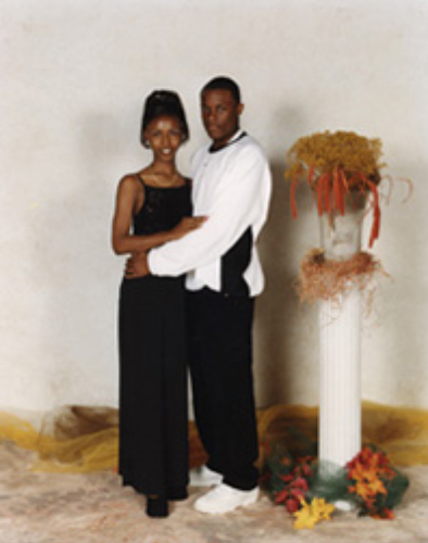 A couple dressed elegantly, posing together indoors.