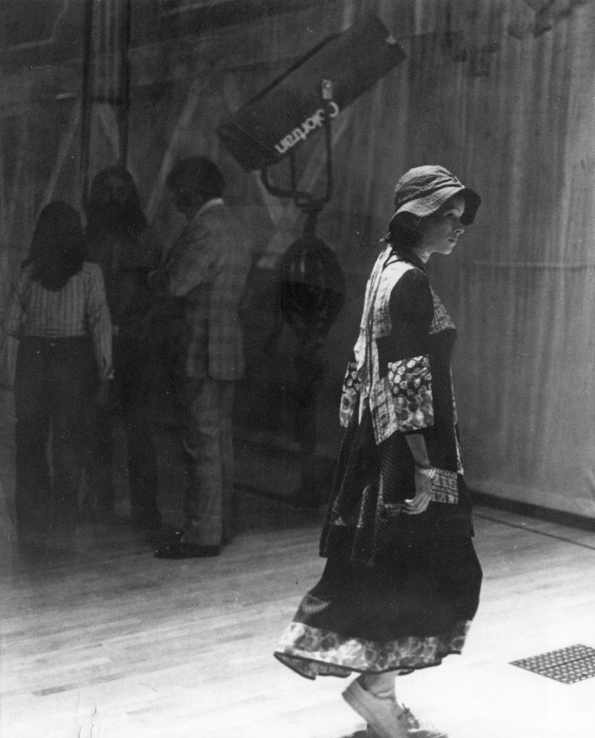 A woman in traditional attire walks past a group of people standing by a wall.