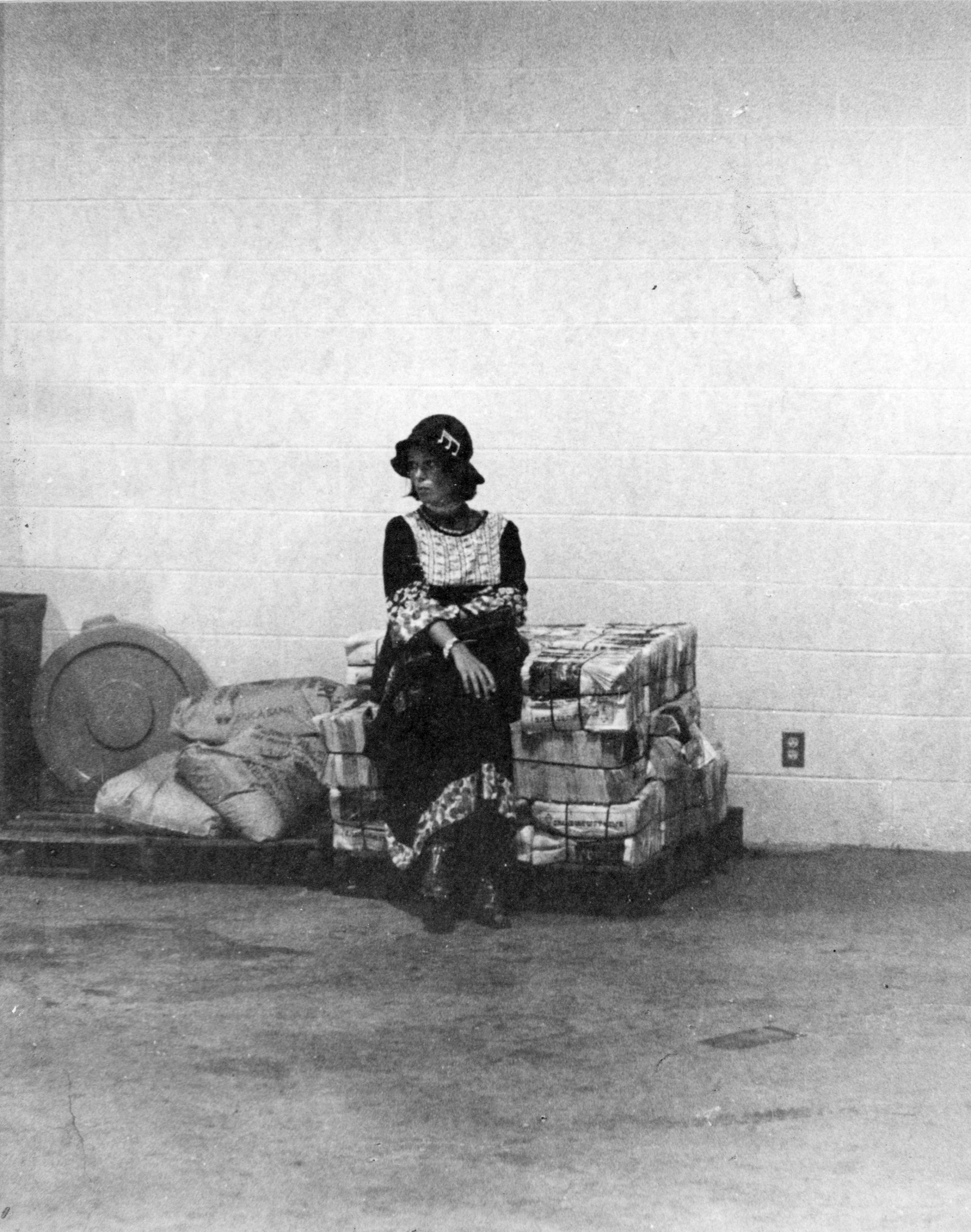 A child sitting alone on a stack of bricks in a sparse room.