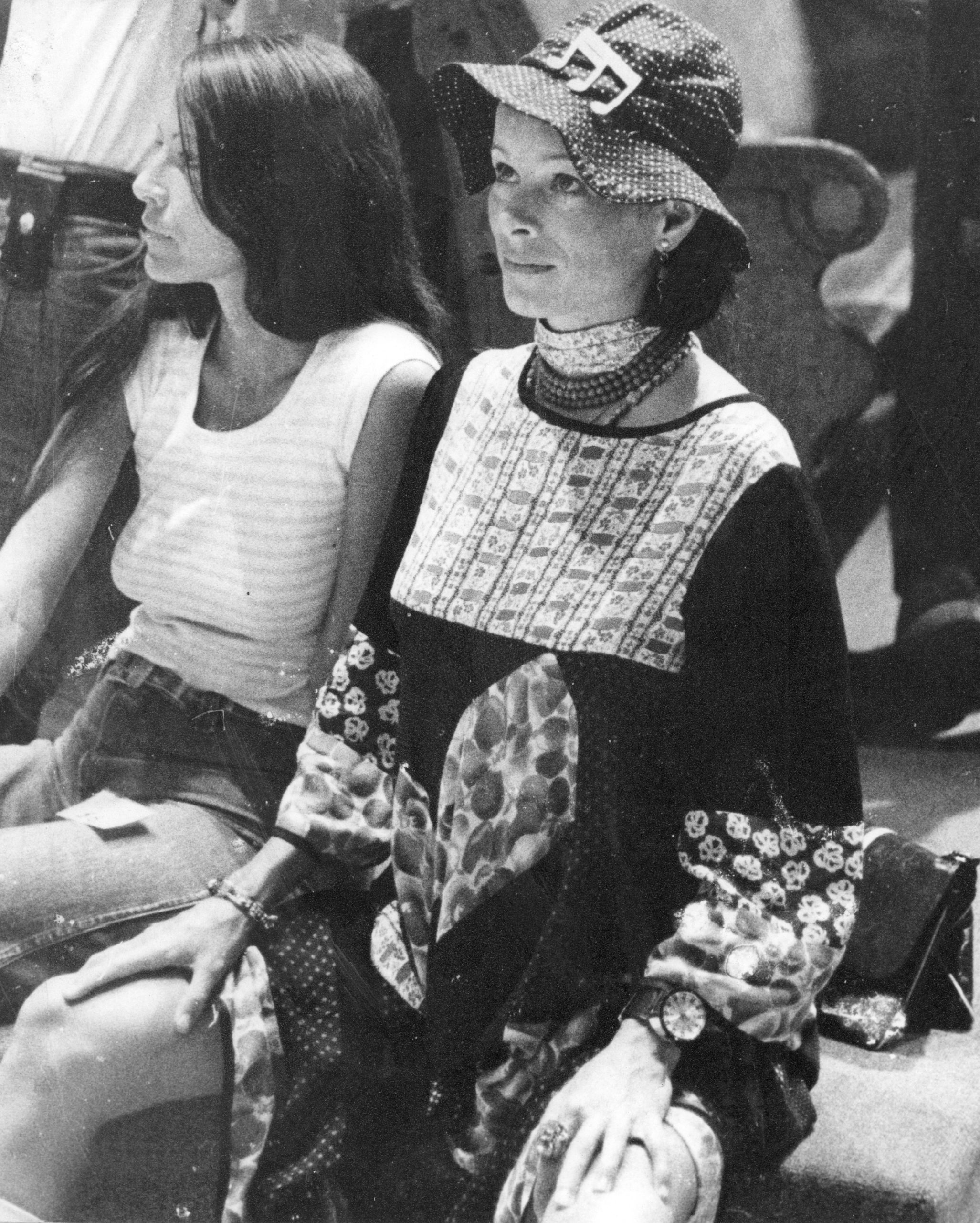 Two women sitting side by side, one in casual wear, the other in traditional attire.