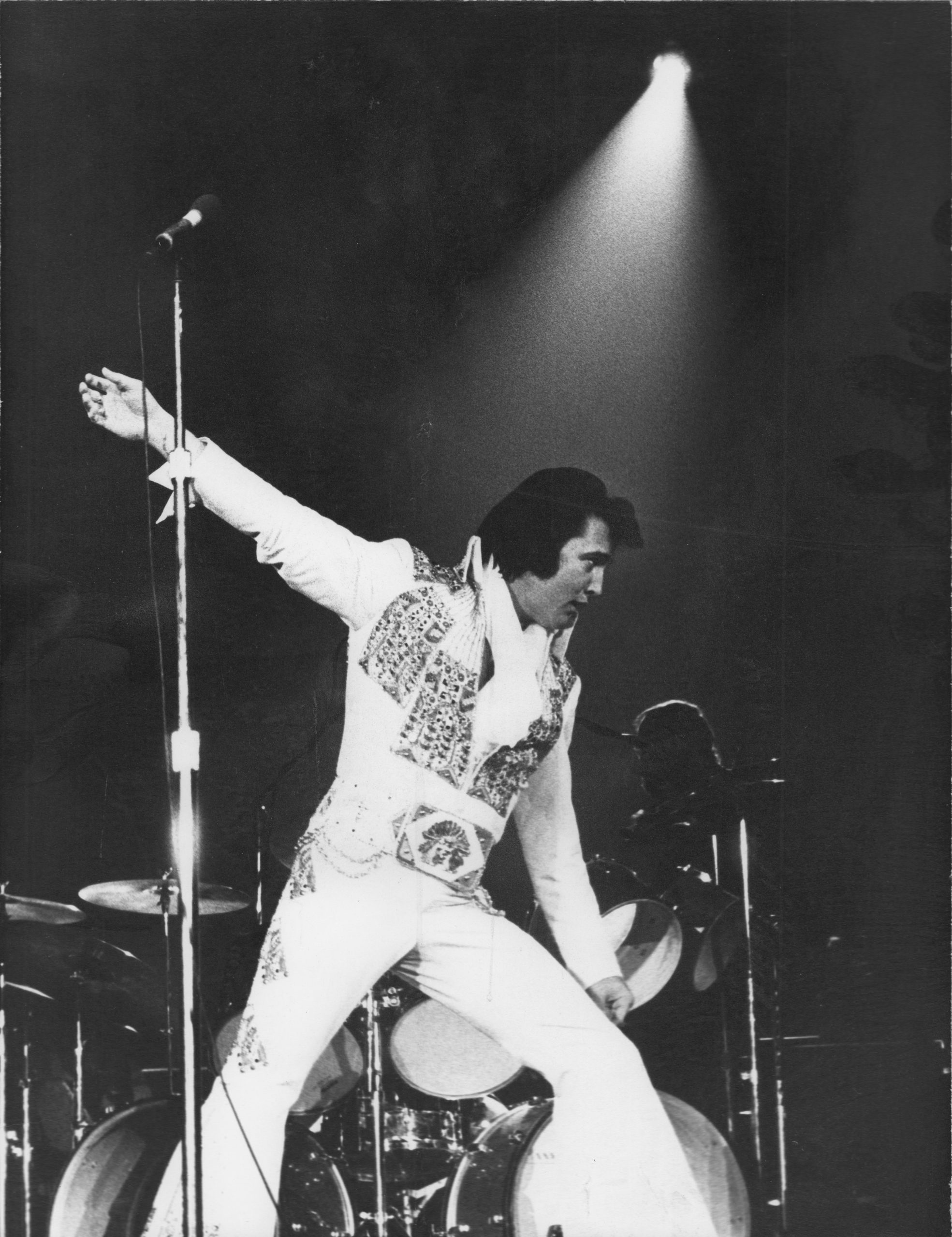 Elvis Presley performing on stage in a classic pose.