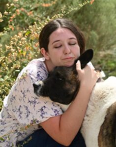 A woman lovingly hugging a black-faced sheep outdoors. A woman lovingly hugging a black-faced sheep outdoors.