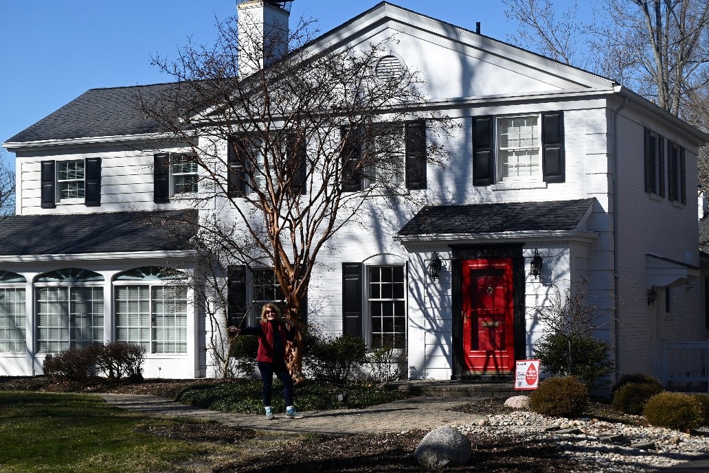 White two-story house with black shutters and a red front door.